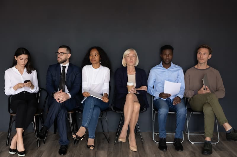 Mehrere Mitarbeiter sitzen auf Stühlen, was sind Generationen am Arbeitsplatz?